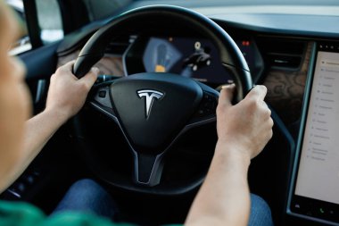 Lviv, Ukrayna - 17 Ekim 2022: Tesla X modeli. Direksiyon kullanan kendine güvenen genç bir adam, harita görüntüleme teknolojisi kullanıyor. Dokunmatik ekran ekranı, aydınlatılmış araba gösterge paneli