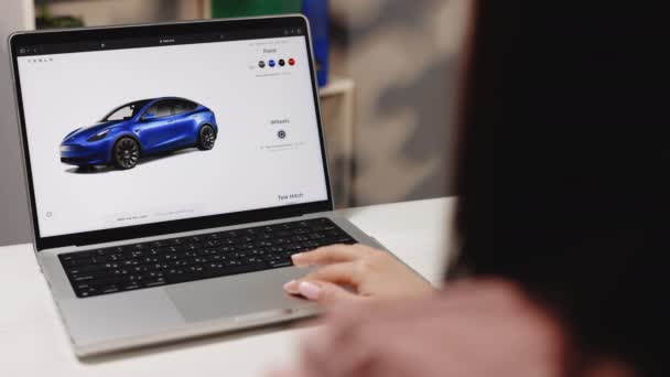 California 11月14 2022 テスラのウェブサイト オンラインで車を購入します テスラモデルY性能と完全自動運転オートパイロットを注文するラップトップコンピュータを使用して女性 ウェブサイトの画面 テスラ — ストック動画