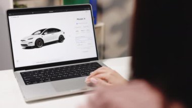 CALIFORNIA, ABD - 14 Kasım 2022: Özel sipariş düğmesi gösteren web siteli laptop ekranı. Tesla web sitesi, internetten araba alıyor. Dizüstü bilgisayar kullanan bir kadın Tesla X modeli ekose sipariş ediyor.