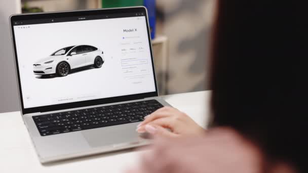 California 2022年11月14日 カスタム注文ボタンを表示するウェブサイトのラップトップ画面 テスラのウェブサイトでは オンラインで車を購入 テスラモデルXを注文するラップトップコンピュータを使用して女性 Play — ストック動画