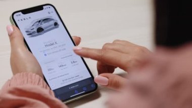 CALIFORNIA, ABD - 14 Kasım 2022: Tesla model X ekoseli ve tam otomatik pilot siparişi. Çevrimiçi Tesla araba alışverişi için akıllı telefon kullanan kadınların ellerini kapat