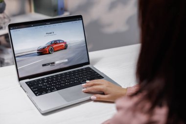 CALIFORNIA, ABD - 14 Kasım 2022: Dizüstü bilgisayar kullanan bir kadın, Tesla 'nın S modelini sipariş ediyor ve otomatik pilot kullanıyor. Web sitesi Tesla Şirketi ile ekran. Tesla web sitesi, internetten araba alıyor.