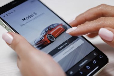 CALIFORNIA, ABD - 14 Kasım 2022: Tesla web sitesinde akıllı telefon kullanarak elektrikli araba satın almak. Tesla Model 3 için alışveriş yapmak satın alma niyetiyle farklı renklerde gezmek.
