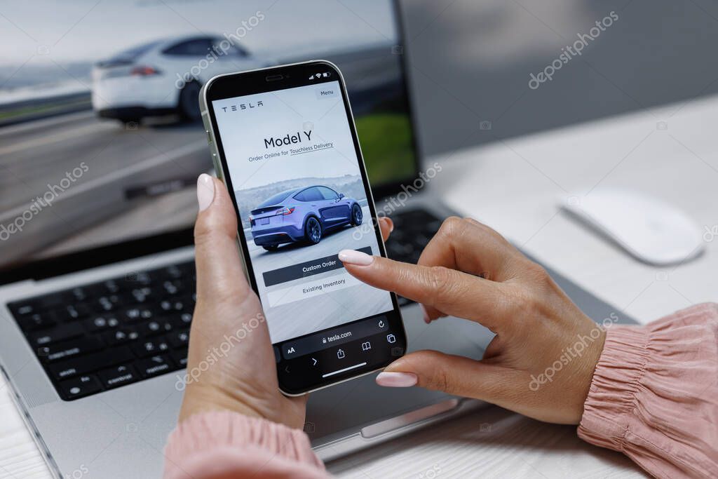 CALIFORNIA, USA - NOVEMBER 14, 2022: Smart phone shopping for a Tesla car browsing different models with the intent to purchase the vehicle online. Ordering Tesla model Y.