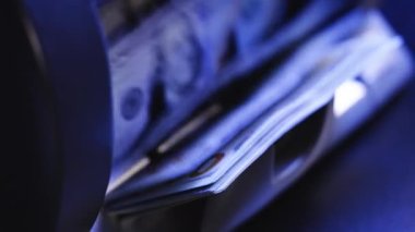 Close up of currency counting machine counting dollar banknotes. Bank automatic equipment for counting paper money. USA federal fed reserve note fragment. Closeup cash money counting equipment.