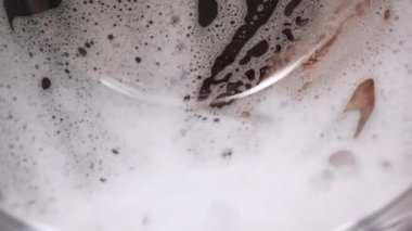 Washing machine in the process, wash clothes in the washing machine, close-up of cleaning clothes. Colorful laundry spinning in drum of washing machine with white soap bubbles.