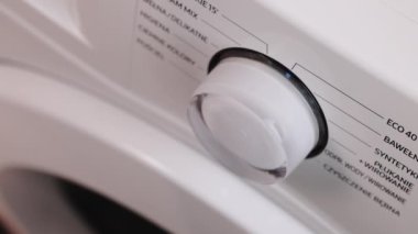 Close Up Shooting with a Hand Rotating the Front Panel Button, Switching Off the Laundry Machine from Eco Mode. A Washing Machine Being Turned On At 30 Degrees To Save Energy And The Environment