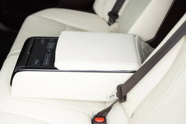 Rear leather passenger seats in modern lux car. Control unit with electric seat adjustment media system for rear passengers in luxury car. Modern car interior detail.