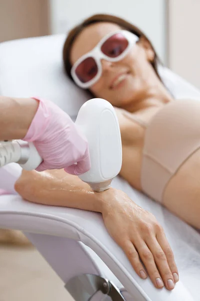 Young woman getting laser hair removal treatment on wrist, close-up. Dermatology, photorejuvenation. Cosmetic clinic. Laser epilation. Hair removal depilation. Sugar bodycare.