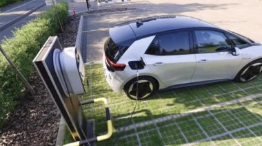 Elektrikli araba araçları şarj oluyor. Elektrikli araç, arabanın fişini takıyor. Elektrikli arabalar için şarj istasyonu. Elektrik, sıfır kirlilik arabaları modern şehir otoparkında yeşil enerji kavramı.