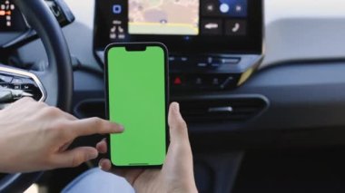 Telefonun yeşil ekranı arabadaki krom anahtar. Sürücü arabada oturuyor ve gün içinde yeşil ekranlı akıllı telefonunu izliyor. Bir arabanın arka planında cep telefonu tutan adam..