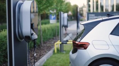 Elektrikli araba istasyonu. Elektrikli arabalar için şarj istasyonu. Elektrikli araba şarj aleti. Şarj istasyonunda elektrikli arabalar. Modern şehir otoparkında yeşil enerji konseptinde sıfır kirlilik arabaları.