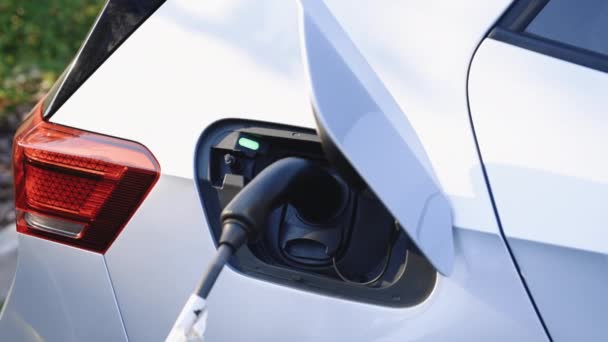 Evモダンカーに接続する電気自動車充電ポート 未来の持続可能なエネルギーの代替エネルギーを節約する 市街地の駐車場の電源ケーブルが付いている現代電気自動車の充満電池 — ストック動画