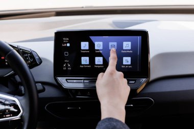 Otomobilinin içinde dokunmatik ekranı olan bir adam. Adam kendi lüks arabasının gidonunun önünde oturuyor. Modern elektrikli otomobiller için akıllı bir multimedya dokunmatik ekran sistemi kullanan erkek parmak.
