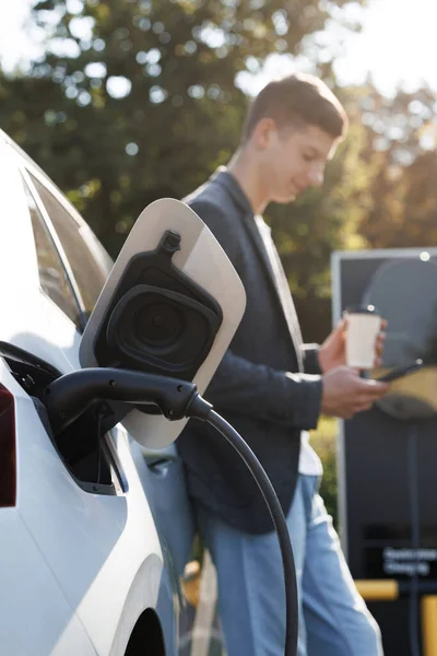 Beyaz Adam Akıllı Telefon Kullanıyor Elektrikli Araçlarla Bağlantı Kuruyor Arabadaki — Stok fotoğraf