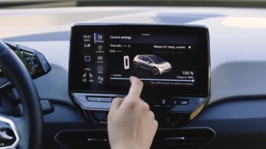 Lviv, Ukrayna - 19 Ağustos 2023: Yeşil enerji, sıfır emisyonlu araç iç görünümü. Uzun menzilli elektrikli araç. Modern otomobiller için akıllı multimedya dokunmatik ekran sistemi kullanan erkek parmak..