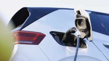 Şehrin caddesindeki otoparkta elektrik kablosuyla şarj edilen modern elektrikli araba. Elektrikli araç modern EV 'yi şarj ediyor. Ekoloji alternatif enerjisini gelecek sürdürülebilir olarak kaydet