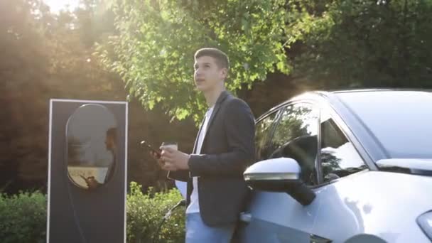 乌克兰利沃夫 2023年8月19日 站在电动汽车旁边的人 正在充电 并在智能手机上调整时间 大众汽车Id3电动汽车在充电站堵塞并充电 — 图库视频影像