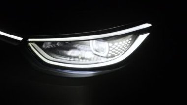 Farlar gece araba LED farlarını kapatıyor. Yeni modern elektrikli araba farları. Arabanın önünü kapatın. IQ 'su Kara Arkaplan Işığına yol açın..