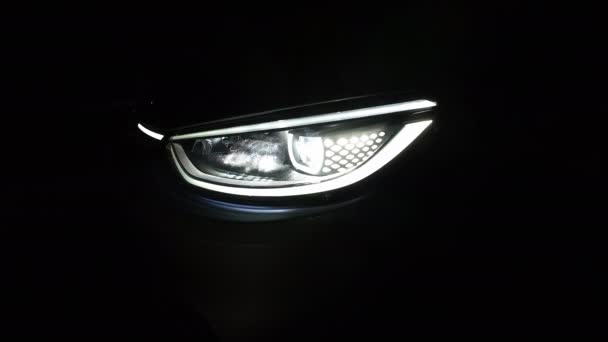 車の前部Iqの閉鎖は黒い背景が付いているライトを導きました 夜の車Ledヘッドライトの切り替えをオフにするヘッドライト 新しい現代電気自動車のヘッドライト — ストック動画