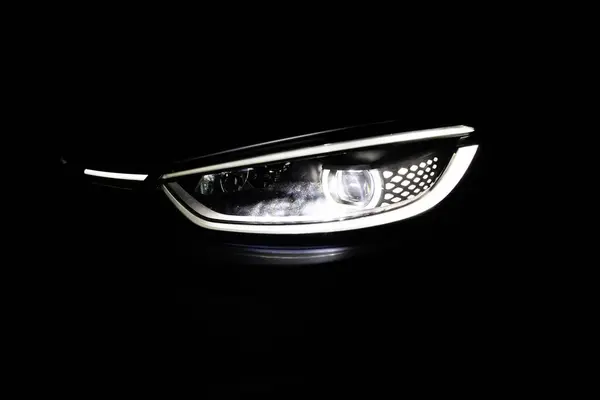 Headlight turning off switching of car LED headlights in night. New modern electric car headlamp. Close up of car front IQ Led Light with a Black Background.