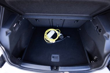 Arabanın bagajında elektrikli araba şarjı var. Elektrikli araba. Şarj kablolarıyla dolu bir araba bagajı. Modern araba iç mekanı, araba bagajı. Bir arabanın bagajında duran elektrikli araba şarjı için taşınabilir kablo şarj kutusu..