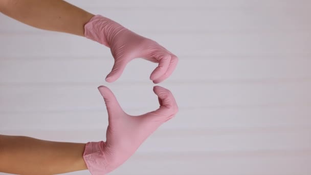 Pionowe Wideo Osoby Różowych Rękawiczkach Lateksowych Pokazujące Gest Serca Białym — Wideo stockowe