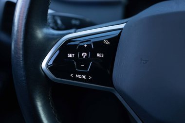 Close up of steering wheel of a new electric vehicle. Electric car control devices. Cruise control buttons, speed limitation, cars signal. clipart