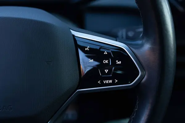 Close-up view of car interior. View of steering wheel of car control music. Volume button of car radio on steering wheel. Turns up the volume of the music in the car