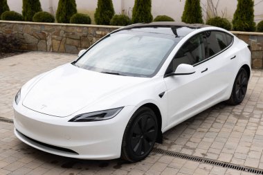 Lviv, Ukrayna - 23 Mart 2024: Beyaz Tesla Model 3 Highland elektrikli araba galeride, çağdaş Avrupa 'da EV kullanımındaki eğilimler, otomotiv endüstrisindeki son teknolojiler, çevresel sürdürülebilir.