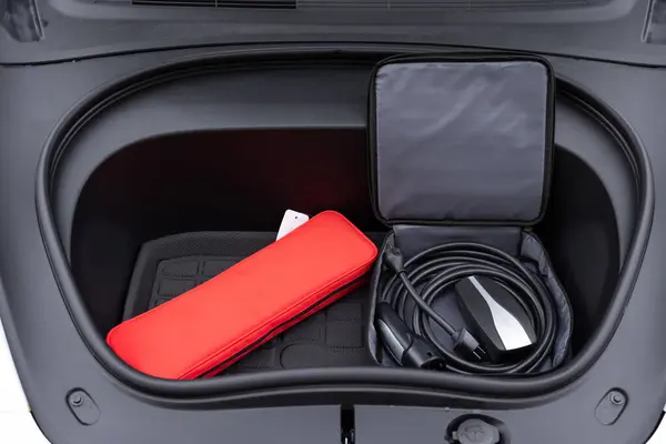 Electric car charger in car trunk. Front trunk with charging cables. Modern interior. Portable in-cable charging box for electric car charging lying in car trunk