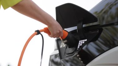 Evdeki ya da şarj istasyonundaki hibrit elektrikli aracın şarj fişi için elektrikli araba kablosu tutan kadına yakın durun. Dünya Çevre Günü. Dünyayı kurtar hayat kurtar kavramı.