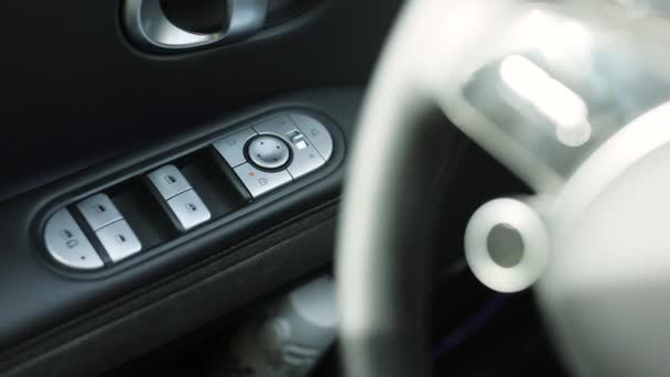 車のドアを閉めるためのボタンは アームレストに手で押されます 車内インテリアのクローズアップビュー ドライバーのドアの窓および鏡のコントロール パネル 現代電気自動車の細部 — ストック動画