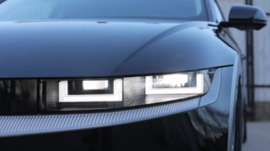 Araba Ön Ön Ön Ön Ön Ön Ön Ön Ön Ön Ön Ön Işık. Lüks arabanın ışıklarını açtı. Yanıp sönen araba. Sürekli yanıp sönen modern elektrikli araba farları yanıp sönüyor..