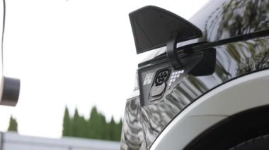 Elektrikli arabasının fişini takan bir kadının ellerini ya da elektrik şarj istasyonundaki EV 'yi yakın çekimde çek. Elektrikli araç modern EV 'yi şarj ediyor. Geleceğin ekolojisini kaydet.
