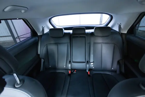 Luxury car rear leather seats row. Interior of new modern clean expensive car. Passenger seats with leather. Closeup details. New electric car inside. Car cleaning theme.