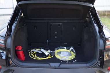 Şarj kablolarıyla dolu bir araba bagajı. Arabanın bagajında elektrikli araba şarjı var. Elektrikli araba. Modern araba iç mekanı, araba bagajı. Bir arabanın bagajında duran elektrikli araba şarjı için taşınabilir kablo şarj kutusu..