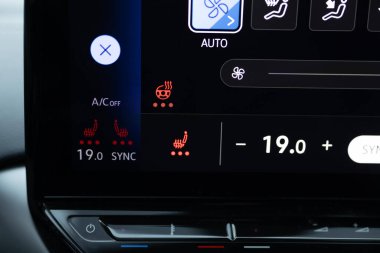Direksiyon ısıtma düğmesi arabada. Isıtmalı koltukları tuşlara basarak çalıştırmak. Arabada ısıtmalı koltuk paneli. Direksiyon simidi ve koltuk ısıtıcısı olan elektrikli araba kontrol paneli.