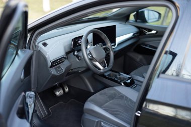 İçinde elektrikli araba iç konforu var. Direksiyon, torpido, hız göstergesi, ekran. Gri deri iç döşeme. Modern lüks araba. Direksiyon, vites kolu ve gösterge paneli..
