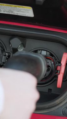 Elektrikli aracın dikey format videosu tip 2 şarj ediliyor. Kadın elleri elektrikli otomobilinin fişini çekiyor. Kadın eli, ereksiyon halatlı bir araba yerleştiriyor. Elektrikli eko araba şarjı.