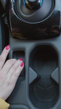 Parmak 'ın araba park etme tuşuna bastığı dikey format videosu. Modern bir arabanın iç dekorasyonunu yakından çek. Elektrikli bir arabanın fren düğmesi..