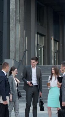 Takım elbiseli bir iş adamının iş arkadaşlarıyla ya da ortaklarıyla konuştuğu dikey format videosu. Erkek lider takım toplantısında işi tartışıyor ya da grup görüşmeleri yapıyor.
