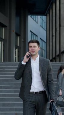 İş Bulma Kurumu 'nun yakınındaki telefonda konuşan yakışıklı iş adamının dikey format videosu. Başarılı bir iş. Klasik takım elbise giyiyordu. Sosyal ağ. Uygulamalar. Akıllı telefonlar.