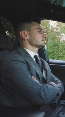 Kendine güvenen bir iş adamının otonom bir araba sürme deneyimini gösteren dikey video. Kendi kendini kullanan, otomatik pilotlu bir arabaya binmek ve otomatik pilot fonksiyonu kullanmak için rahat erkek deneyimi..