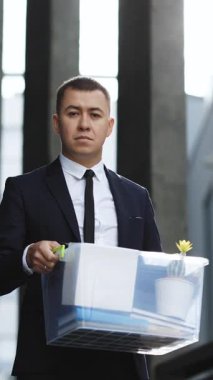 Depresyondaki üzgün erkek ofis çalışanının kişisel eşyalarla dolu dikey videosu. İş adamı işini kaybetti. Kovulan adam dışarıda. Bunalımlı işsiz insan. İşsizlik kavramı. Parasız kaldı.