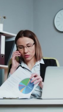 İşkadını 'nın bilgisayarda çalıştığı, bilgisayarında çalıştığı, ofis masasında oturduğu, bilgisayar yazılımı faturalarını modern işyerinde daktilo ederek ödediği dikey video.