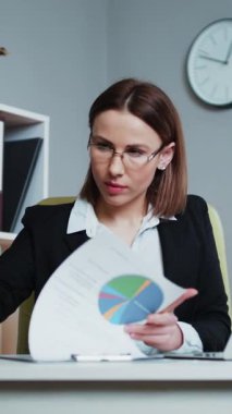 Modern Ofisindeki İşyerindeki Mali Belgelerden Verilerle Çalışan Güvenilir Genç İşkadını 'nın dikey Videosu. İşyerindeki Dalgın İş Kadınları Bürosu çalışanının Portresi.