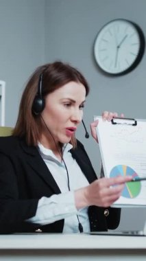 Webcam 'deki Kâğıt Tutucu Kadın Finansal Rapor Konuşması' nın düşey videosu Ofiste Video Görüşmesi, Kamera Konuşma İstatistikleri Müşteri Pazarlama Stratejisini Açıklayan İş Yöneticisi