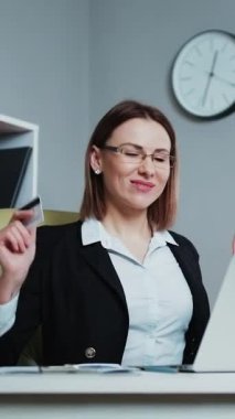 Masasında Otururken Dans Eden Güzel İş Kadını 'nın dikey videosu. Başarılı ve mutlu kadın albüm satışlarını kutluyor. Yaratıcı Genç Kadın Çalışma Masasında Otururken Dans Ediyor.
