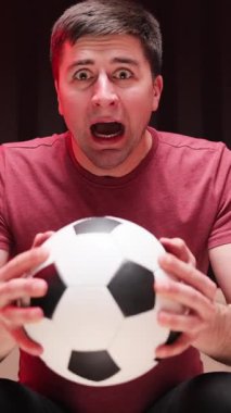 Football taraftarlarının şampiyonluk maçı izlediği dikey video. Genç bir adamın vereceği sevinçle şaşırmış tepki TV izliyor. Spor Hayranları Tepkisi Konsepti. Heyecanlı bir sporcu hayranı TV 'de en sevdiği oyuncuyu izliyor.